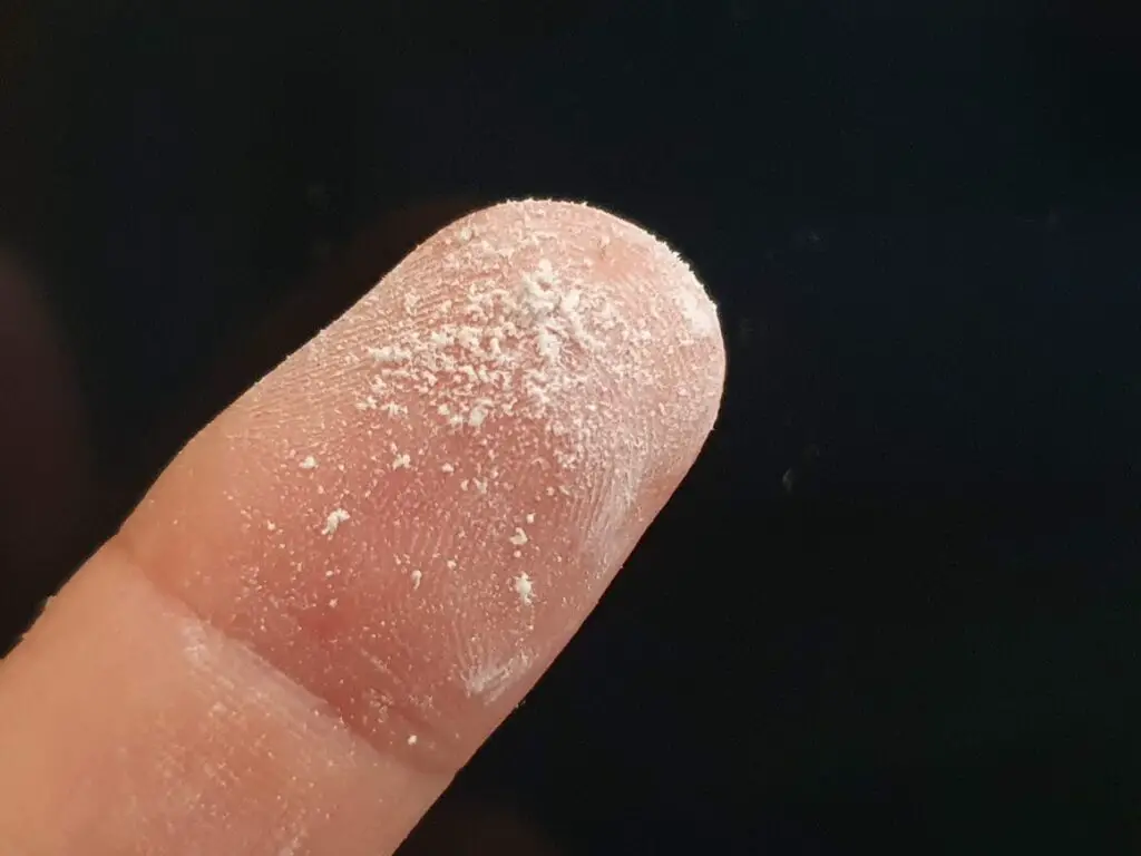 White dust on end of finger.